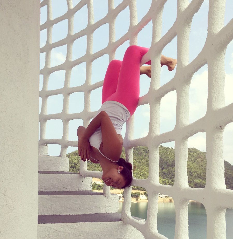 Rachel playfully upside down on a lattice staircase overlooking the water